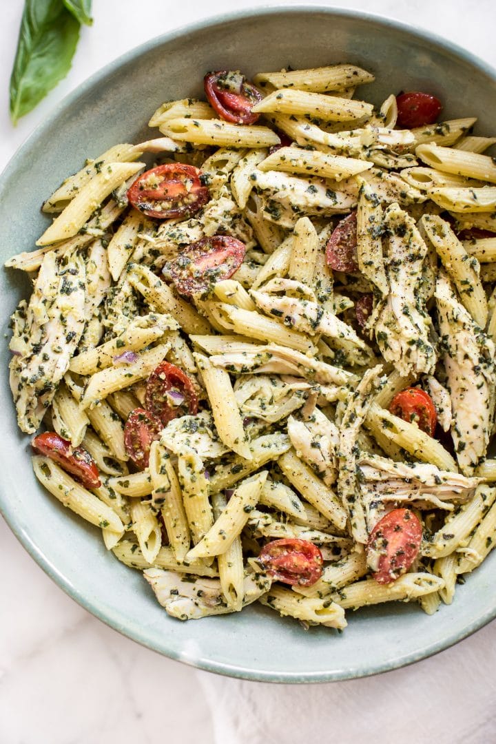 close-up of healthy cold pesto pasta salad with chicken in a teal bowl