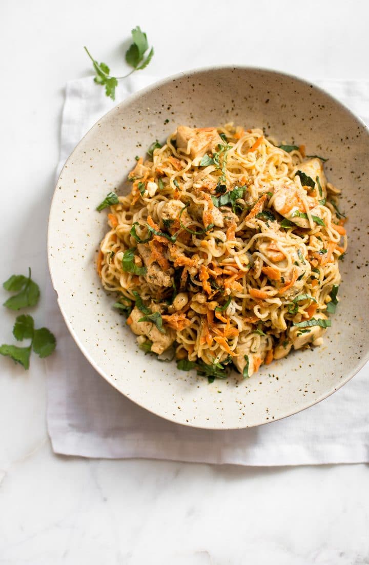 easy chicken ramen noodles stir fry in a bowl with two sprigs of cilantro