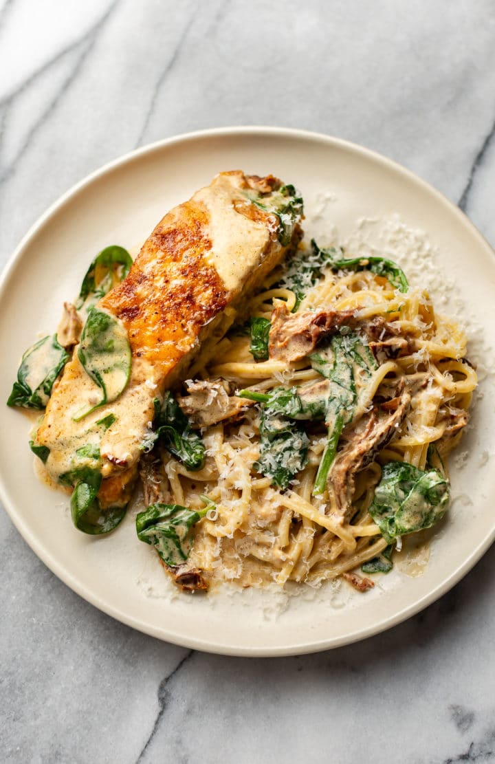creamy Tuscan garlic salmon on a plate with spaghetti and lots of creamy sauce