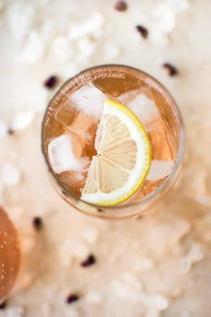 rosé wine spritzer in a glass with ice cubes and lemon slice