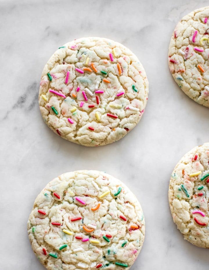 a few rainbow sprinkle cookies on a marble surface