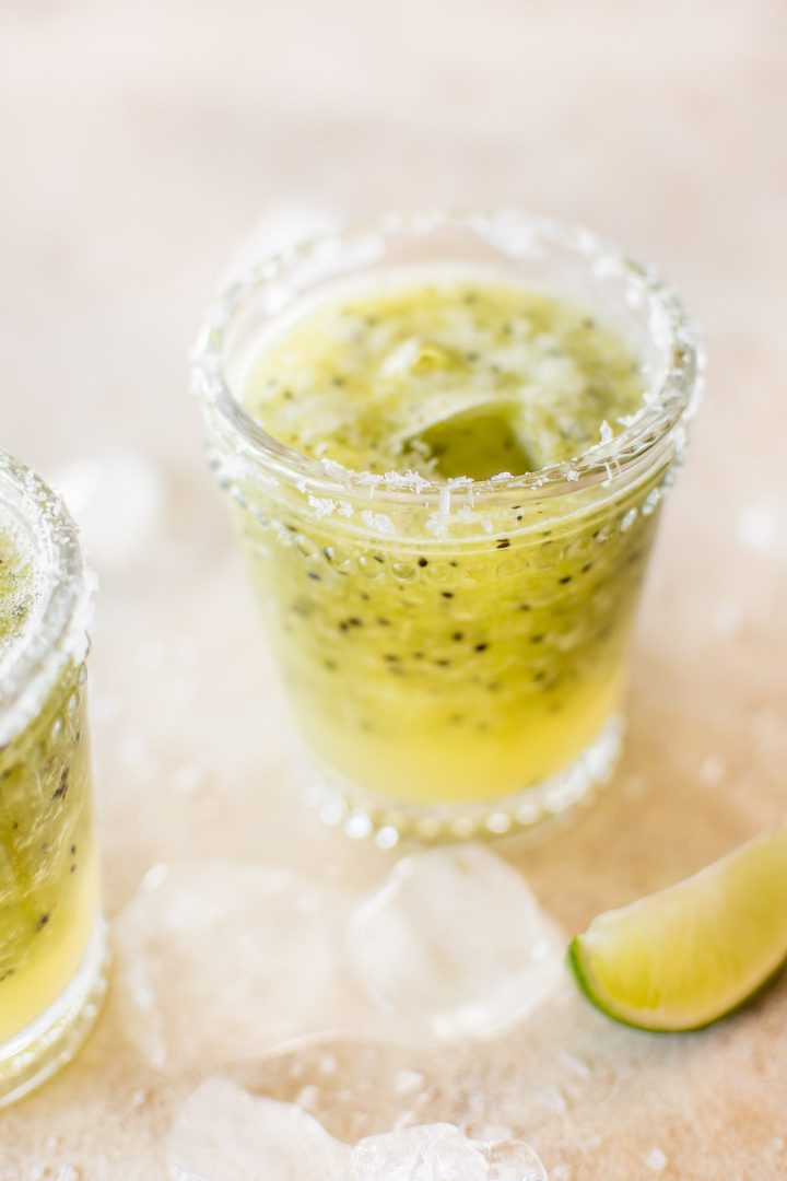 glass filled with kiwi margarita beside lime wedge