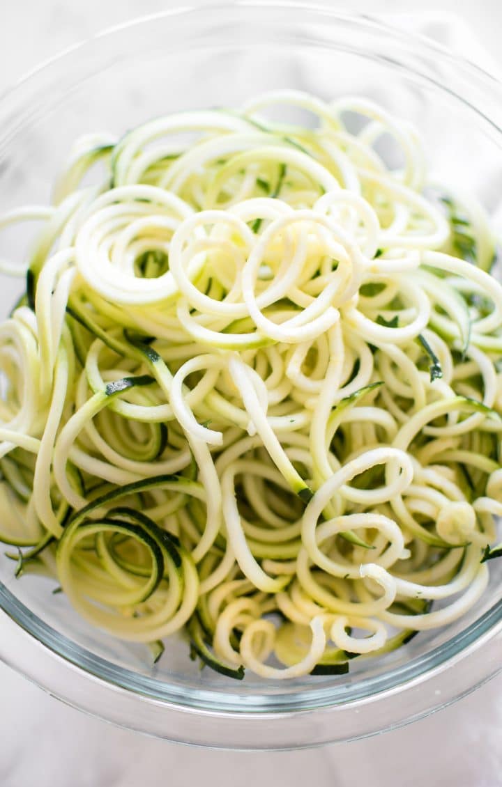 glass mixing bowl with uncooked zucchini noodles