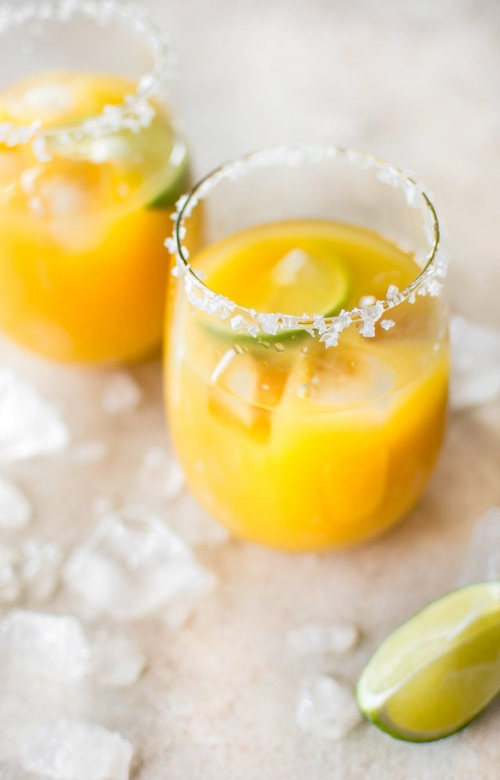 two glasses with mango margaritas and ice