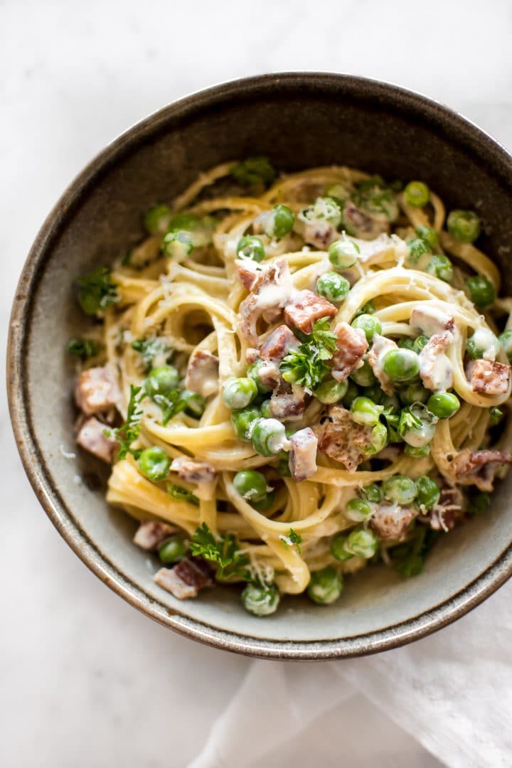 pasta with pancetta, peas, a creamy garlic sauce in a stoneware bowl