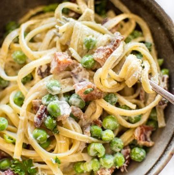 Pasta with pancetta, peas, a creamy garlic sauce, and plenty of fresh parmesan makes an easy and tasty dinner!