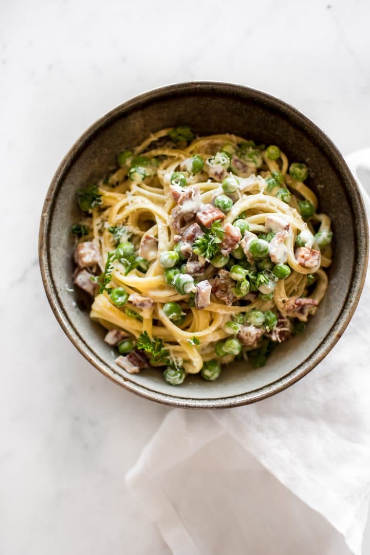 a bowl of creamy garlic pancetta and pea pasta with freshly grated parmesan