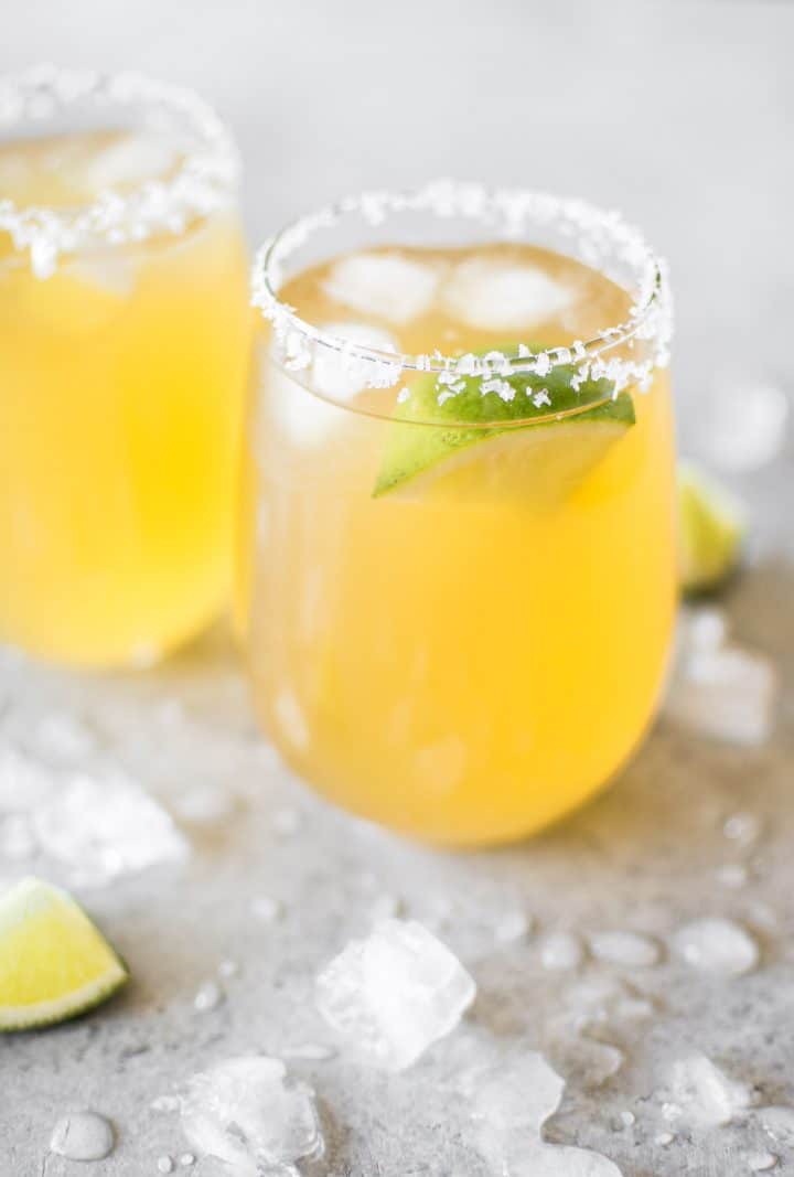 two glasses with passion fruit margarita with lime wedge