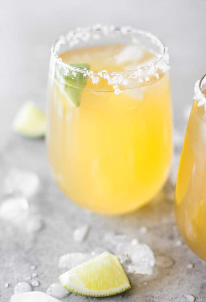 passion fruit margarita cocktail with tequila and fresh lime juice in a clear glass with lime slice