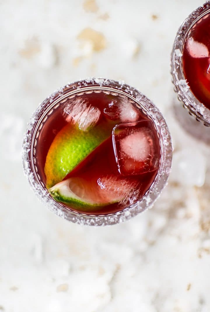 close-up of pomegranate margarita on the rocks with lime wedges