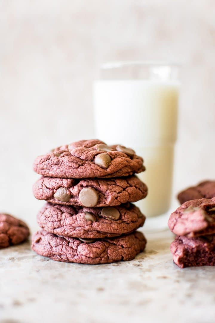 stack of four red velvet cake cookies with a glass of milk in the background