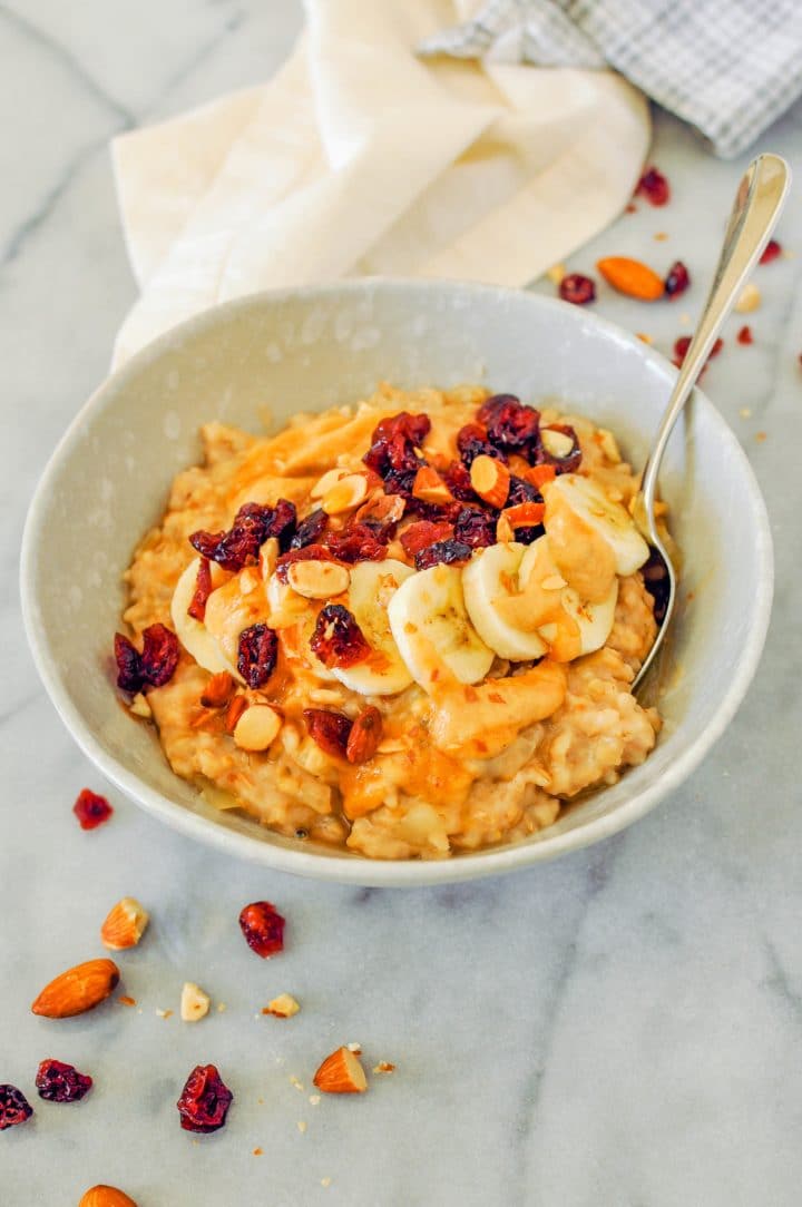 slow cooker peanut butter oatmeal in a bowl with a spoon and banana slices