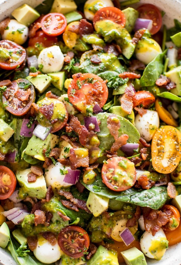 close-up of avocado, bacon, tomato, spinach salad with mozzarella