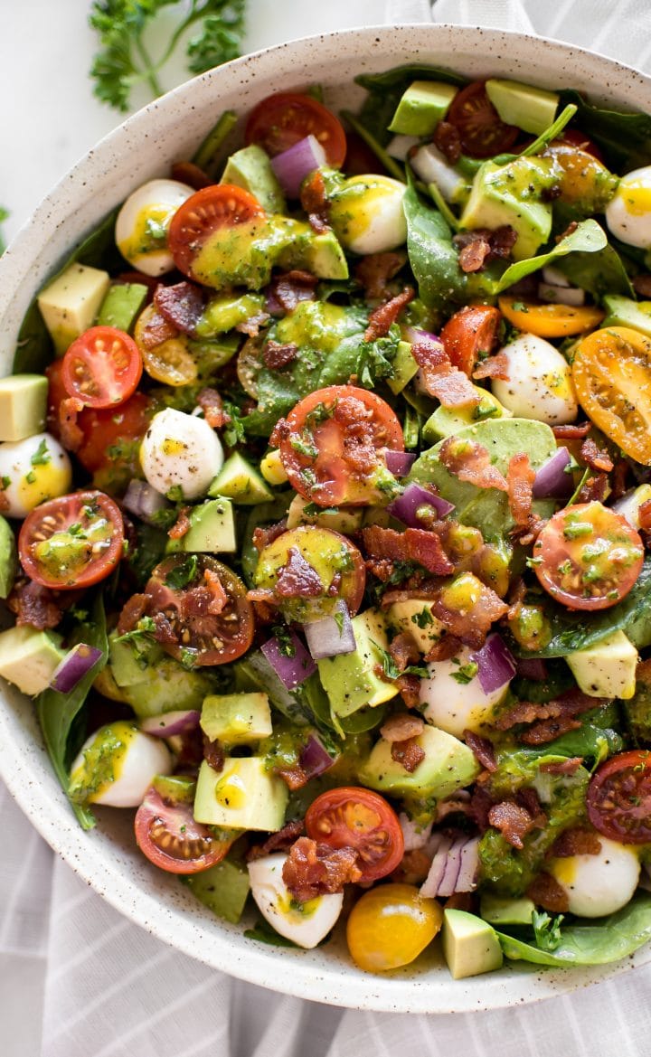 close-up of avocado bacon salad with honey mustard vinaigrette in beige bowl