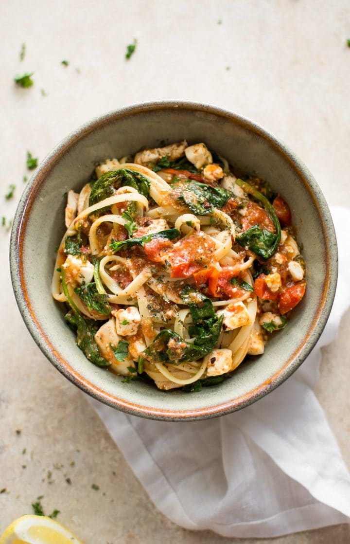 chicken feta spinach pasta in stoneware bowl with a white cloth napkin