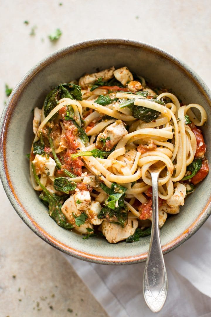 close-up of chicken feta spinach pasta in stoneware bowl with fork