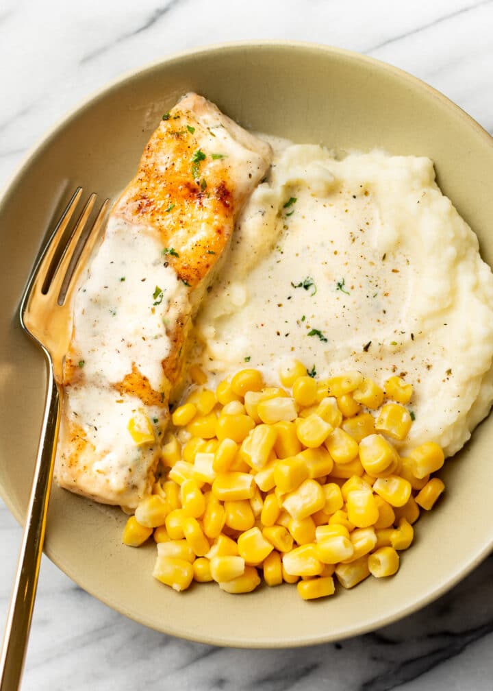 a plate with mashed potatoes, creamy lemon salmon, and corn