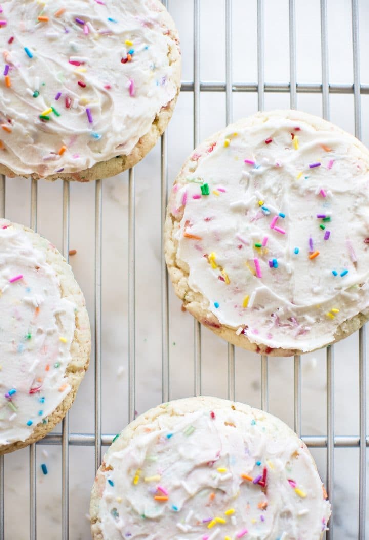 rainbow sprinkles cookies with icing on a wire rack