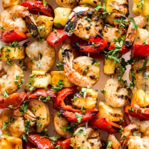 These grilled pineapple shrimp skewers are the perfect easy summer BBQ recipe! The sweet honey glaze, juicy shrimp, and red peppers make the best Hawaiian kabobs.