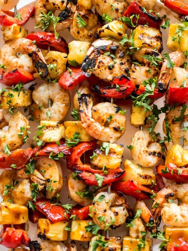 These grilled pineapple shrimp skewers are the perfect easy summer BBQ recipe! The sweet honey glaze, juicy shrimp, and red peppers make the best Hawaiian kabobs.