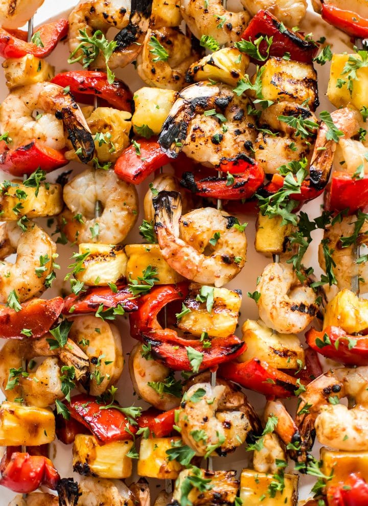 These grilled pineapple shrimp skewers are the perfect easy summer BBQ recipe! The sweet honey glaze, juicy shrimp, and red peppers make the best Hawaiian kabobs.