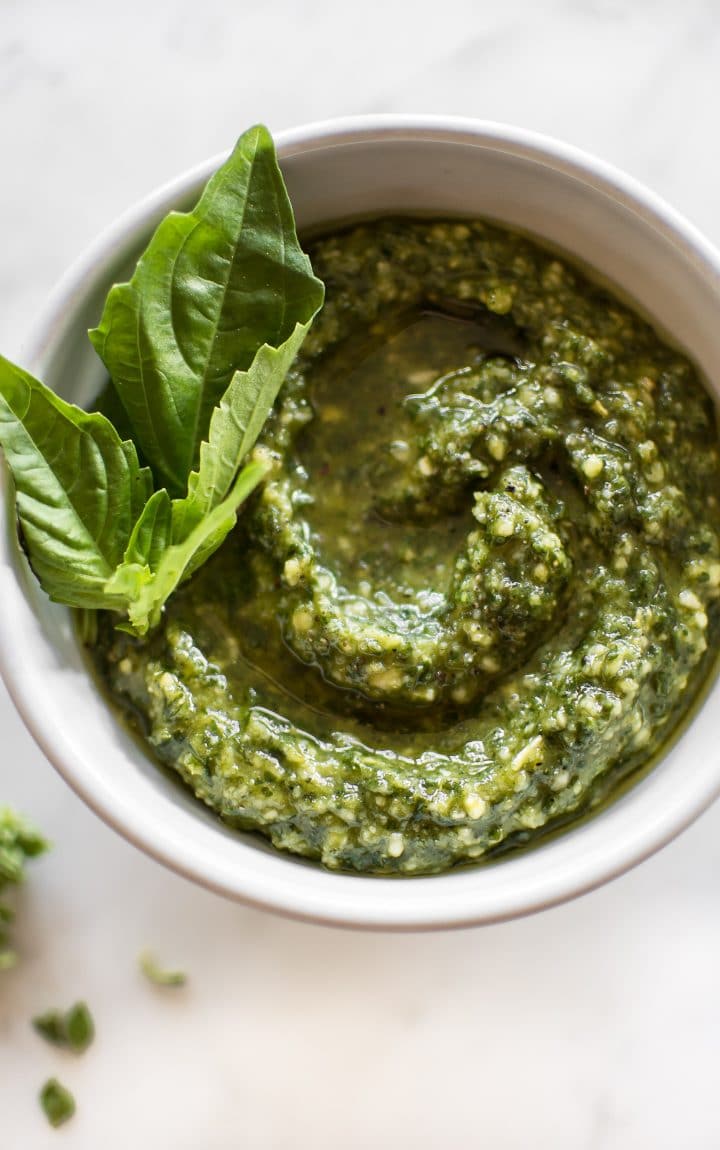 a small bowl with homemade pesto and a sprig of fresh basil