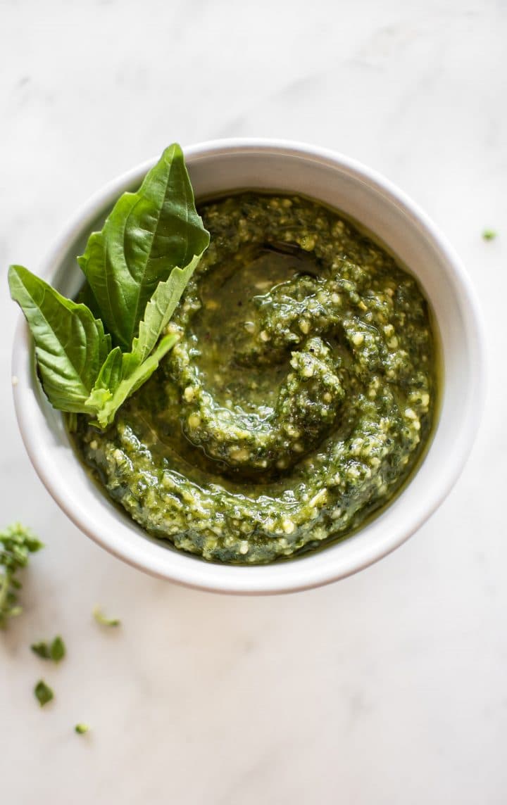 homemade basil presto in a bowl with basil leaves for garnish