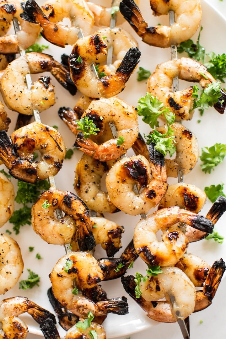close-up of easy honey garlic grilled shrimp skewers on a plate with parsley