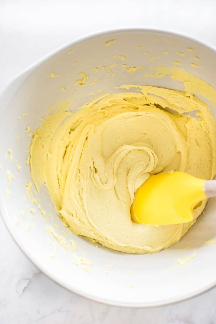lemon cake mix cookie batter in a mixing bowl with a yellow spatula