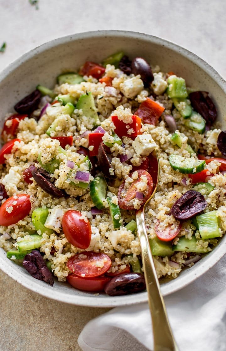 close-up of healthy Greek quinoa salad in a bowl with a spoon