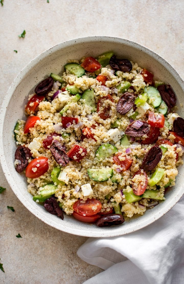 beige serving bowl with Mediterranean quinoa, olive, and tomato salad