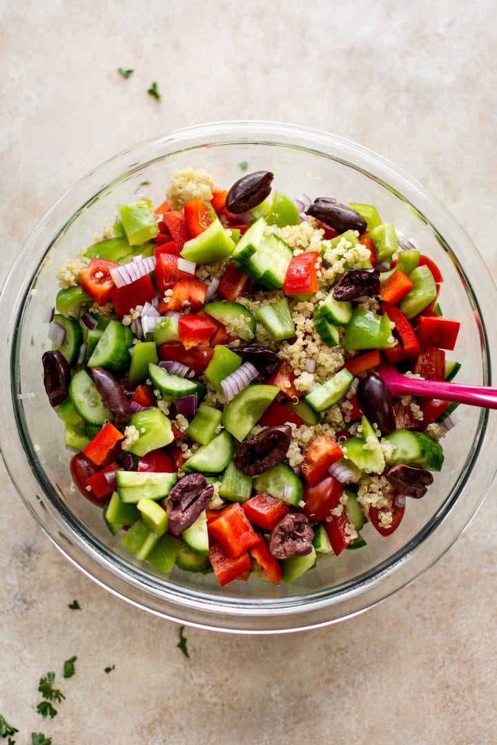 ingredients for Mediterranean quinoa salad in a glass mixing bowl