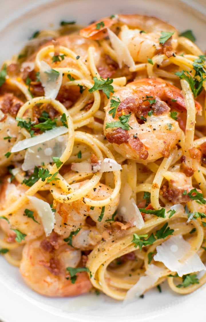 close-up of creamy shrimp and bacon pasta with grated parmesan and parsley garnish