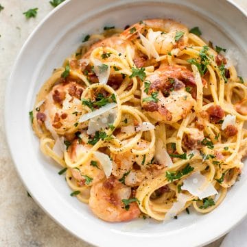 This easy, creamy shrimp pasta with bacon is the perfect weeknight treat or easy dinner party recipe! The sauce is brightened with fresh tomato. Garlic and white wine make the sauce extra delicious.