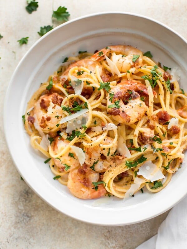 This easy, creamy shrimp pasta with bacon is the perfect weeknight treat or easy dinner party recipe! The sauce is brightened with fresh tomato. Garlic and white wine make the sauce extra delicious. 