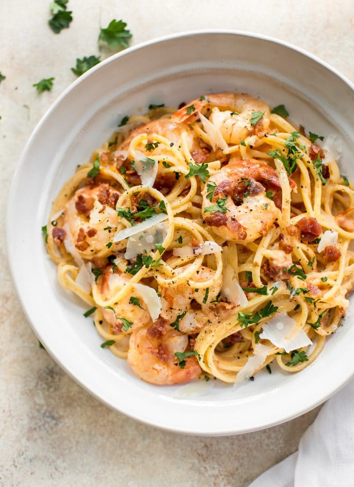 This easy, creamy shrimp pasta with bacon is the perfect weeknight treat or easy dinner party recipe! The sauce is brightened with fresh tomato. Garlic and white wine make the sauce extra delicious. 