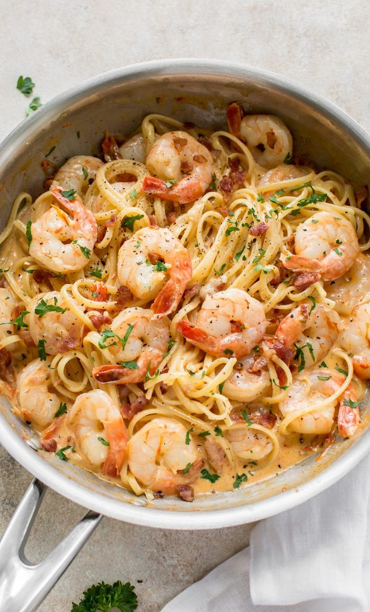 creamy shrimp and bacon pasta in a skillet with parsley garnish