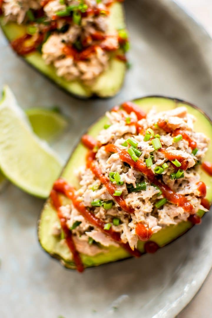 spicy tuna stuffed avocado half beside lime wedges