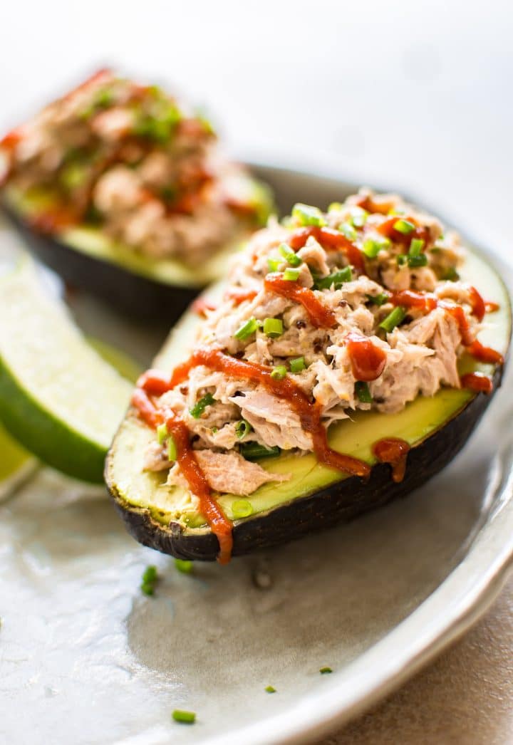 plate with two halves of spicy sriracha tuna stuffed avocado and lime wedge