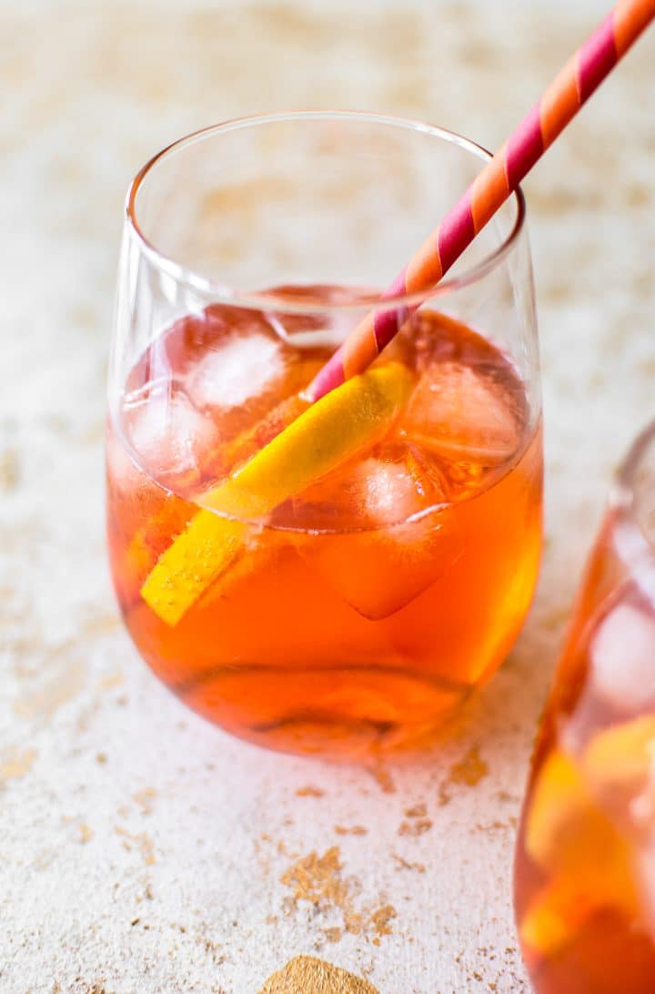 close-up of a glass with aperol spritz cocktail and a straw