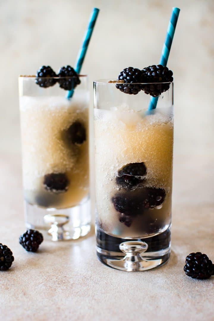 two tall clear glasses of frozen riesling and blackberries with blue straws