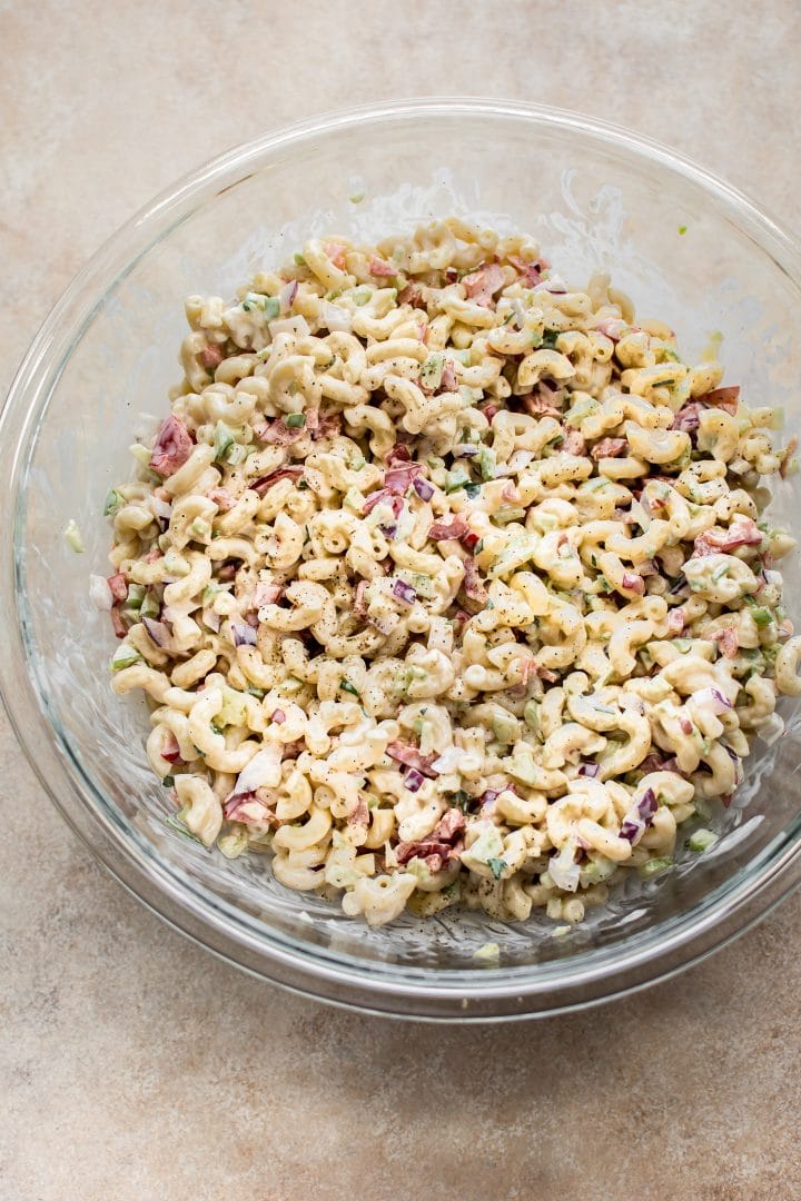 creamy macaroni salad in a clear glass serving bowl