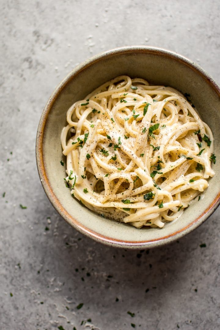 creamy garlic pasta in earthenware bowl on grey surface
