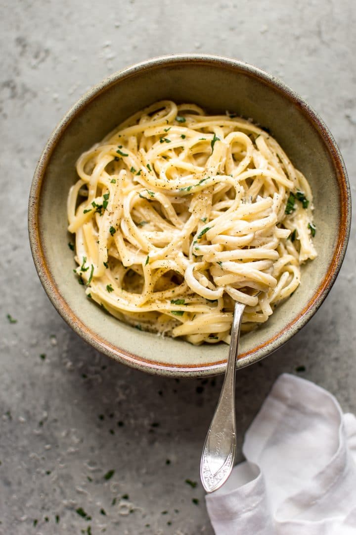 creamy garlic pasta in earthenware bowl with spaghetti twirled on a fork