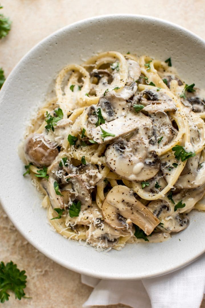 close-up of creamy mushroom pasta with white wine, butter, lemon juice, and cremini mushrooms in a white bowl