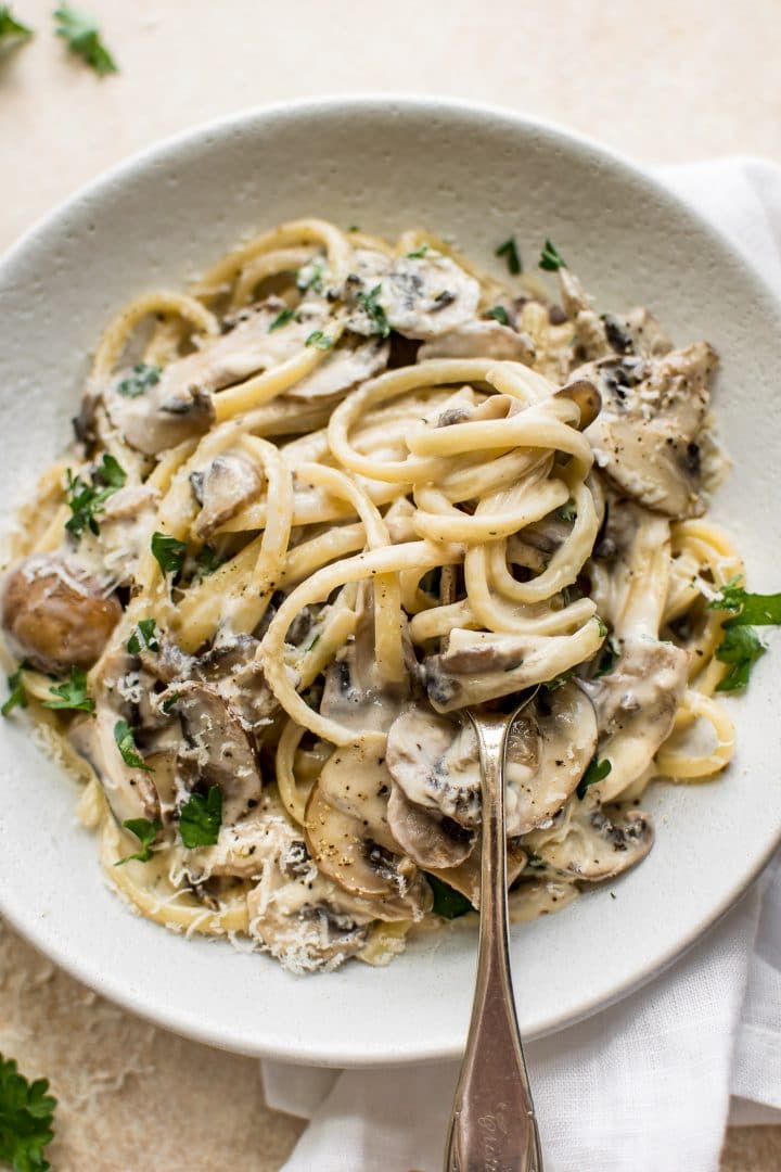 white bowl with creamy vegetarian mushroom pasta and a fork