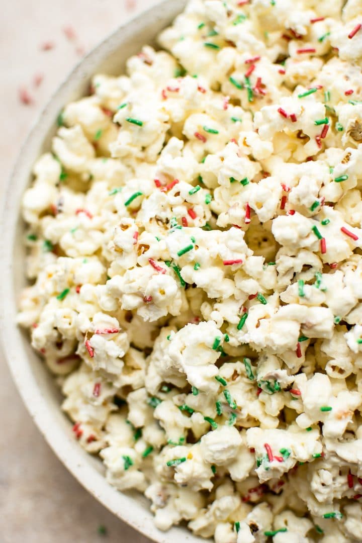 close-up of a bowl of festive popcorn with red and green sprinkles and white chocolate