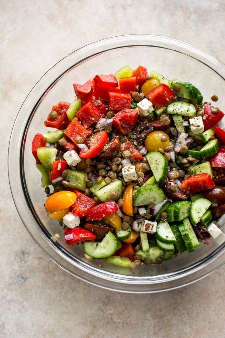 clear glass mixing bowl with mediterranean lentil salad ingredients