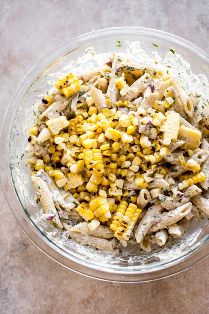 Mexican street corn pasta salad in a clear glass mixing bowl
