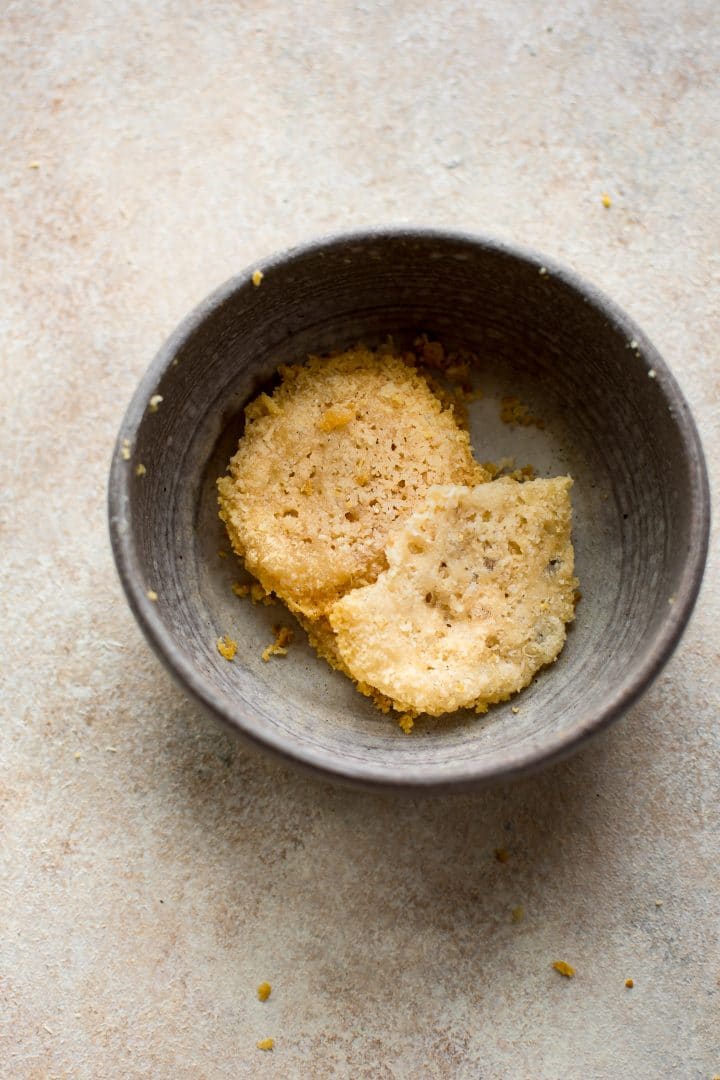 parmesan cheese crisps in grey bowl with crumbs